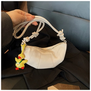 Detail of cream-colored lychee textured shoulder bag with knot strap and duck pendant