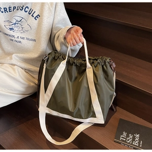 Detail of olive green nylon tote bag with drawstring closure and cream webbing strap