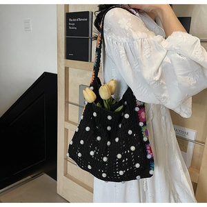 Detailansicht der schwarzen Häkeltasche mit Perlenverzierung und bunten Blumenstickereien