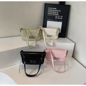 Four colorful shoulder bags with N-shaped buckles displayed on white minimalist steps