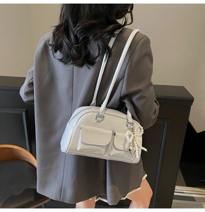 Close-up of light grey patent leather shoulder bag featuring pearl bow and heart charms
