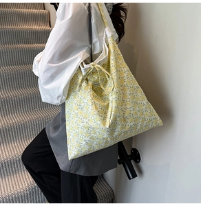 Détail du sac cabas en toile à fleurs jaunes avec nœud décoratif et texture en coton doux