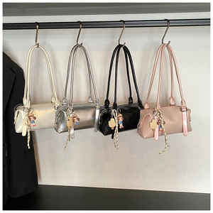 Close-up of four stylish cylinder shoulder bags in ivory, silver, black, and pink colors