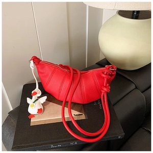 Detail of red crescent bag with lychee texture and cute white duck charm accessory