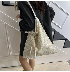 Sac fourre-tout en toile florale avec nœud et dentelle porté par un mannequin en décor