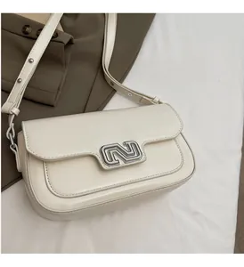 Detail of cream-colored crossbody bag with polished silver-tone logo buckle