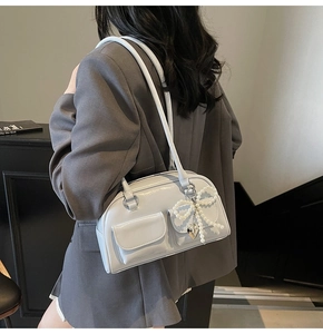 Detail of glossy patent leather shoulder bag with decorative pearl bow and double pockets