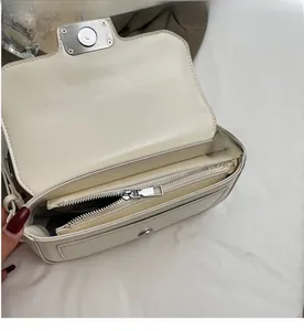 Close-up of cream white handbag featuring a smooth zipper and internal storage compartment