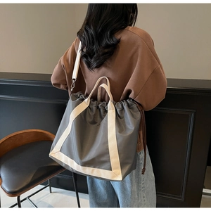 Detail of dark grey drawstring tote bag with off-white straps and spacious design