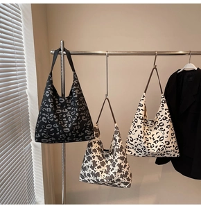 Tres bolsos hobo de lona con estampados de leopardo y vaca colgados en un soporte de metal