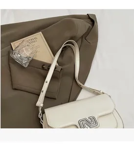 Detailed macro view of the silver letter N buckle and leather texture on a white handbag