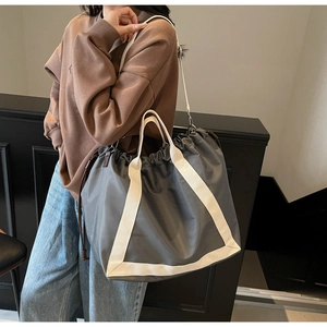 Detail view of grey drawstring tote bag with off-white straps and durable nylon texture