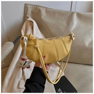 Close-up of a yellow crescent handbag with pebbled leather and duck charm