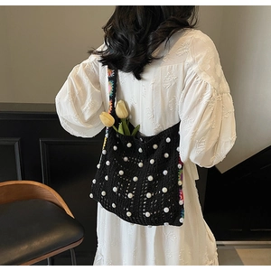 Detail der handgewebten schwarzen Häkeltasche mit Perlen und Blumenstickerei