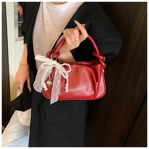 Detalle del bolso de cubo plisado rojo con lazo de encaje y adornos de perlas