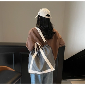 Rear view of grey drawstring tote bag with white triangle webbing and crossbody strap