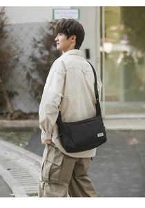 Black nylon dumpling bag with adjustable shoulder strap and large front zip pocket