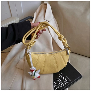 Detail of yellow crescent handbag featuring lychee texture and cute duck charm