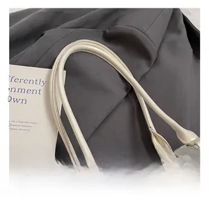 Detail of comfortable pearl white faux leather handle and metallic ring on shoulder bag