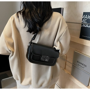 Detailed view of black leather crossbody bag featuring a silver N-shaped metallic buckle