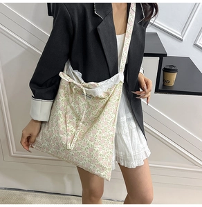 Détail du sac cabas floral en toile avec bordure en dentelle, nœud et étiquette slogan