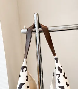 Detalle del bolso tote con estampado de vaca, correa de cuero sintético y costuras