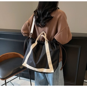 Close-up of black nylon tote bag with drawstring closure and contrasting white straps