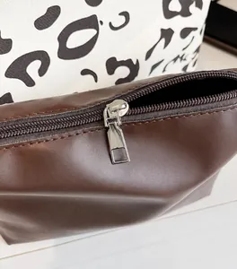 Primer plano de la cremallera metálica en bolso de cuero marrón con fondo de estampado de vaca