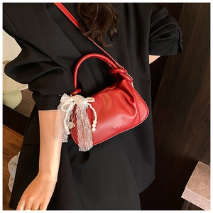 Detalle de bolso saco rojo fruncido con lazo de encaje y adornos de perlas finas