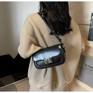 Detail of a black glossy leather crossbody bag with silver geometric logo buckle