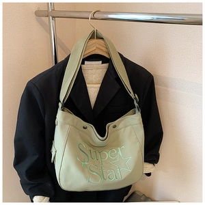 Détail du sac en toile vert menthe avec imprimé Super Star sur cintre en bois