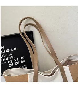 Detail van de versterkte kruisstiksels op de leren handvatten van een canvas tote tas