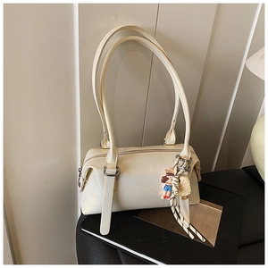 Detail of cream white faux leather shoulder bag featuring decorative pendant and top zipper