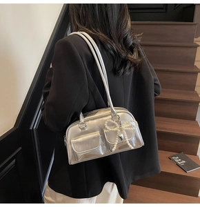 Silver metallic pillow bag with front flap pockets shown as a crossbody on model