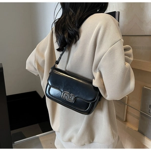 Detail of vintage black glossy shoulder bag featuring silver geometric metal clasp and strap