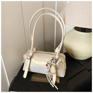 Detail view of cream shoulder bag with glossy finish and cute cartoon charms