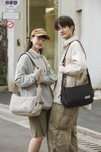 Close-up of waterproof nylon dumpling bags in black and beige on models in urban setting