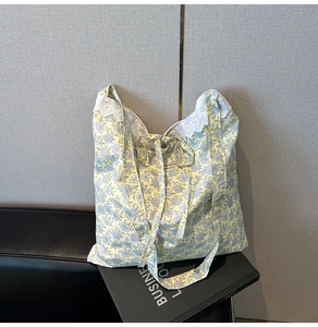 Détail du sac cabas floral avec bordure en dentelle blanche et nœud sur banc en cuir
