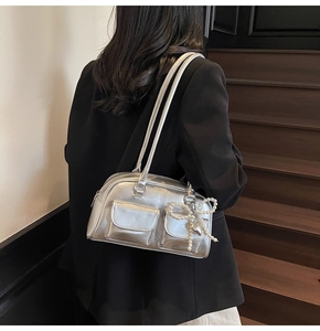 Close-up of metallic silver shoulder bag featuring dual front pockets and pearl bow charm