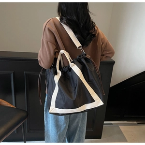 Detail of black nylon tote bag with white contrast straps and drawstring closure