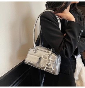 Silver metallic shoulder bag with pearl bow and heart charm on a black blazer