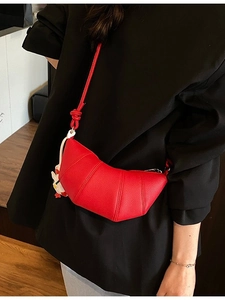 Red lychee pattern leather croissant bag with a cute duck charm on black outfit background