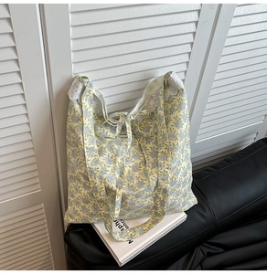 Détail du sac cabas floral jaune avec bordure en dentelle blanche et nœud élégant