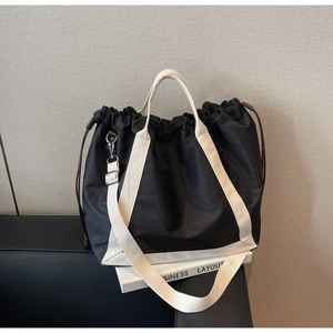 Detail of black nylon tote bag with drawstring closure and contrast woven straps