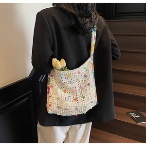 Detail einer Häkeltasche mit bunten Perlen und geblümtem Schultergurt aus Strick