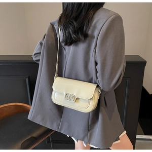 Detailed close-up of cream square handbag showing silver geometric lock and glossy finish