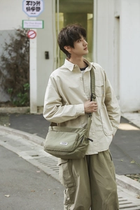 Detailed shot of olive green nylon messenger bag featuring adjustable strap and woven brand label