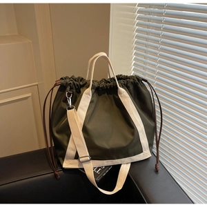 Detail of army green nylon bucket bag with cream webbing straps and drawstring closure