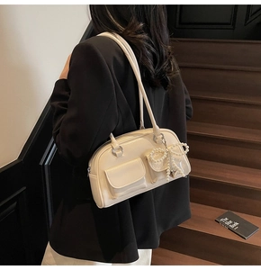 Chic cream patent leather shoulder bag with side pockets and pearl bow charm detail