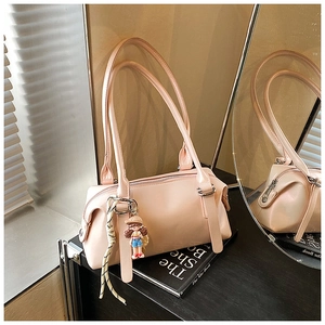 Detail of pink glossy pillow bag featuring a cute doll pendant and reflective mirror view